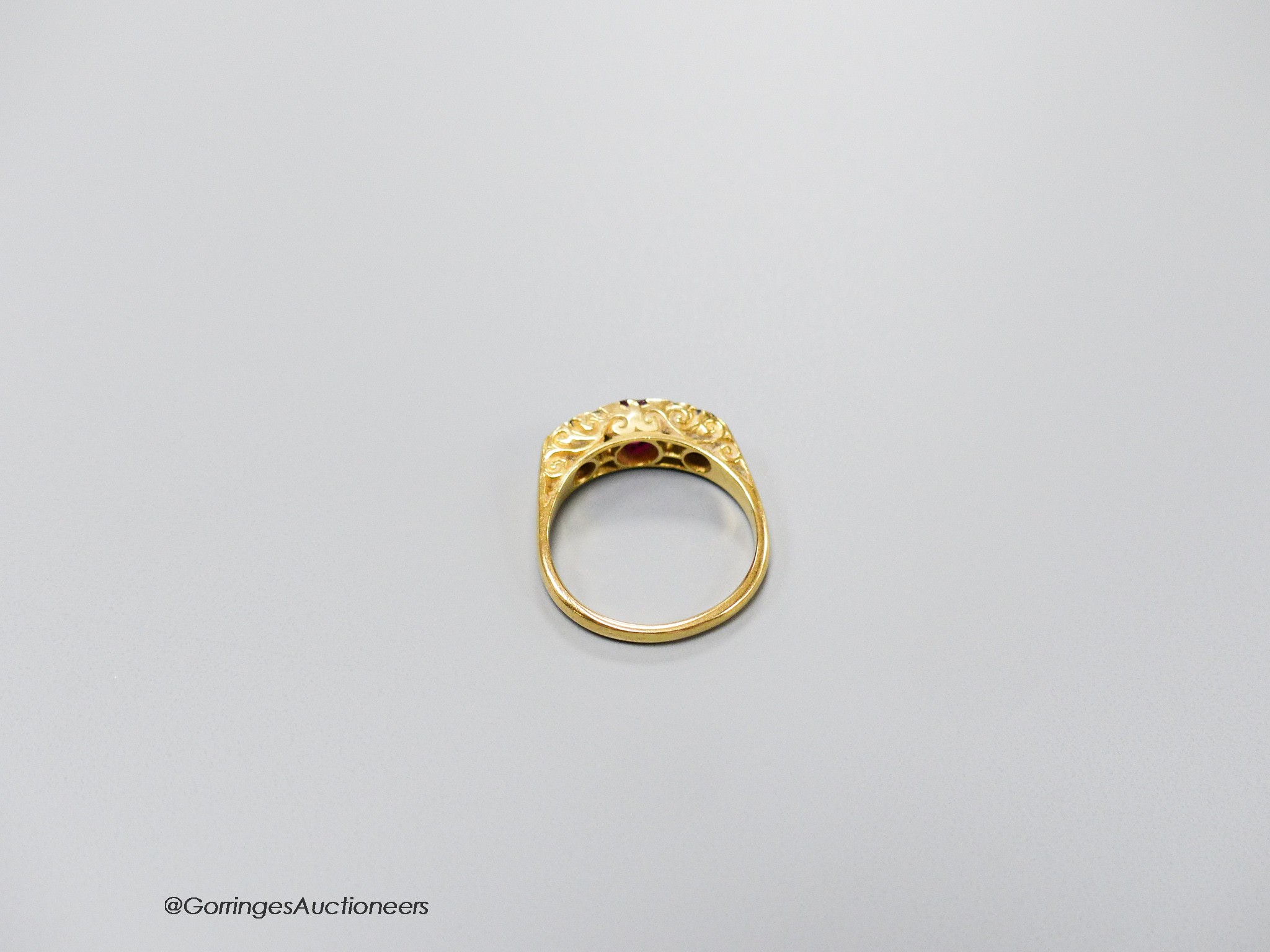 An early 20th century 18ct, three stone ruby and four stone diamond chip set half hoop ring, size L, gross 4.1 grams.